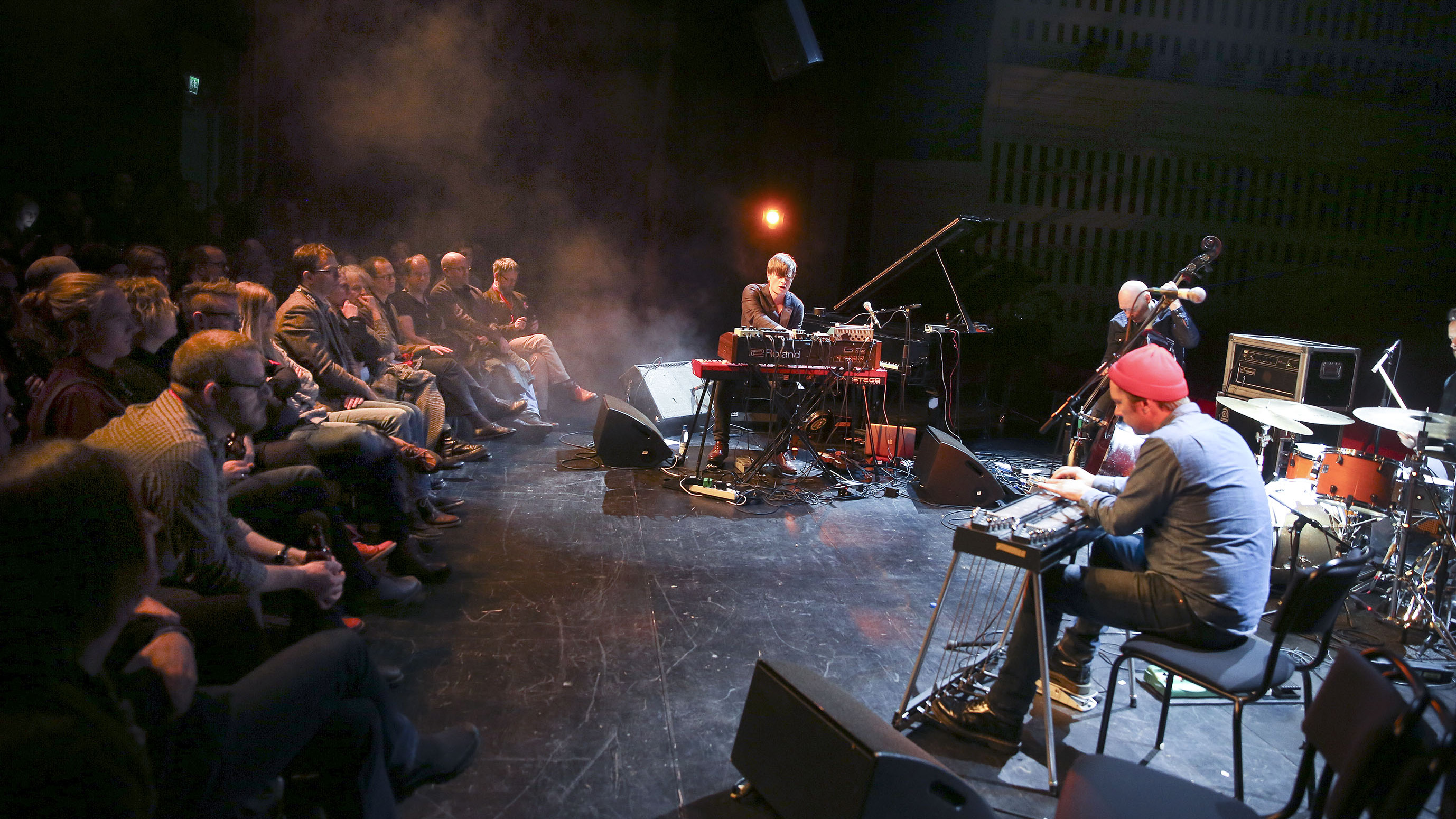 En publik som tittar på musiker som spelar på scenen.