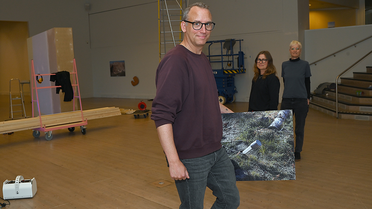 En man håller i en tavla i Konsthallen.