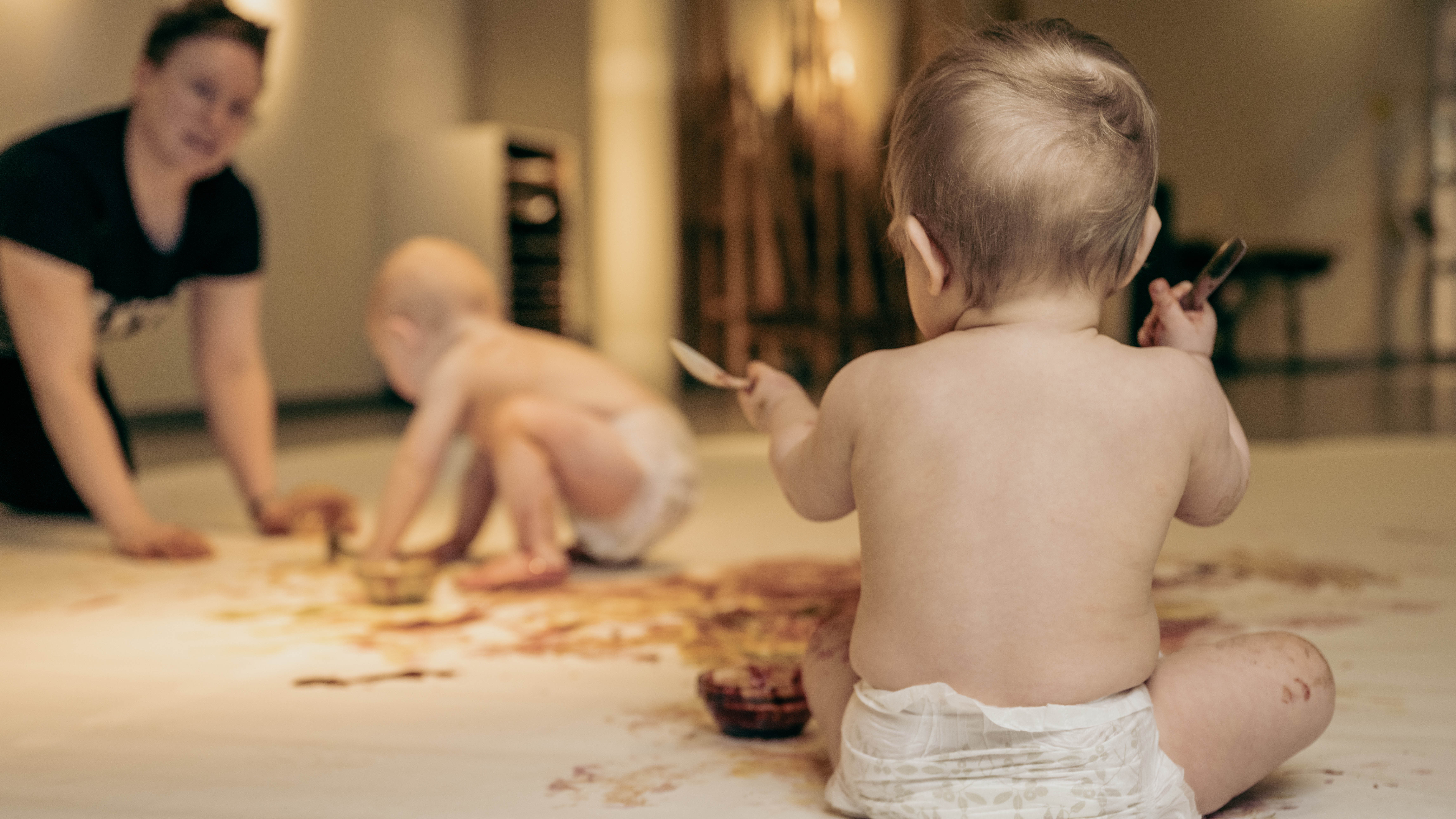 Två bebisar i bara blöja som målar med ätbara färger.